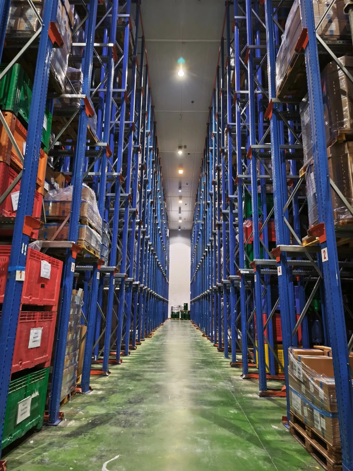 Pasillo de un almacén logístico con estanterías de gran altura cargadas de palés