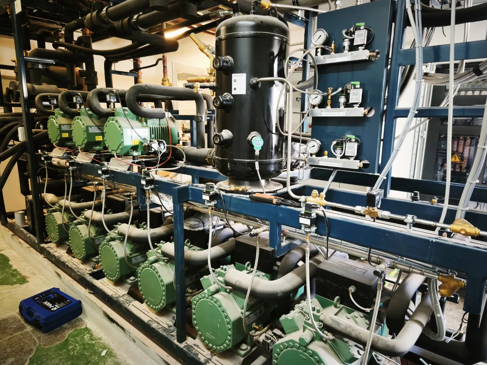 Central frigorífica industrial con varios compresores, recipiente de líquido y panel de presostatos