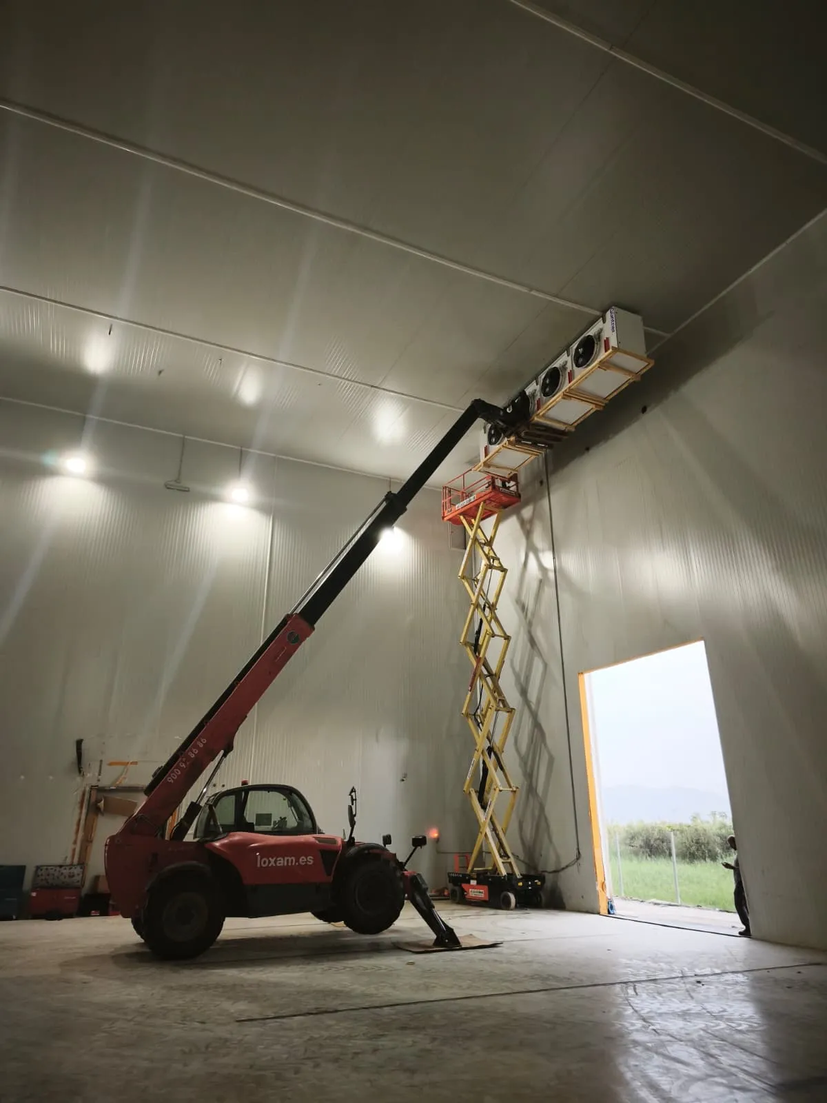 Montaje de un evaporador en el techo de una cámara frigorífica de gran altura con plataforma elevadora